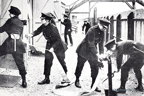 Uniformed Fire Women Performing Fire Drill In A Munitions Work