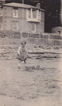 A Little Girl Looking Sadly At Her Sandcastles