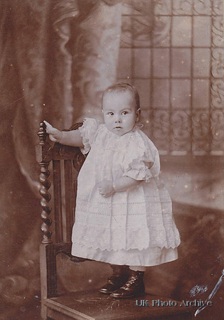A Victorian Child With A Long Dress & Button Up Boots