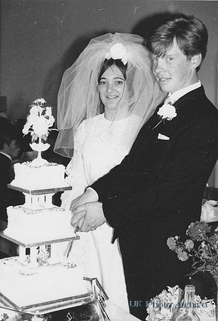 A 1960s Bride and Groom Cutting The Wedding Cake