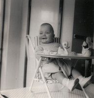 A Baby In A Highchair With Toy Duck And Clown c.1950s