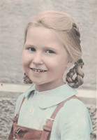 A Little Girl Wearing Dungarees With Plaits In Her Hair