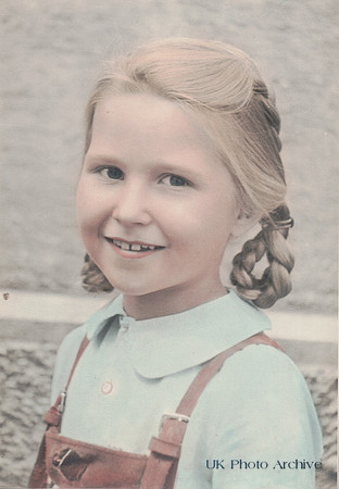 A Little Girl Wearing Dungarees With Plaits In Her Hair